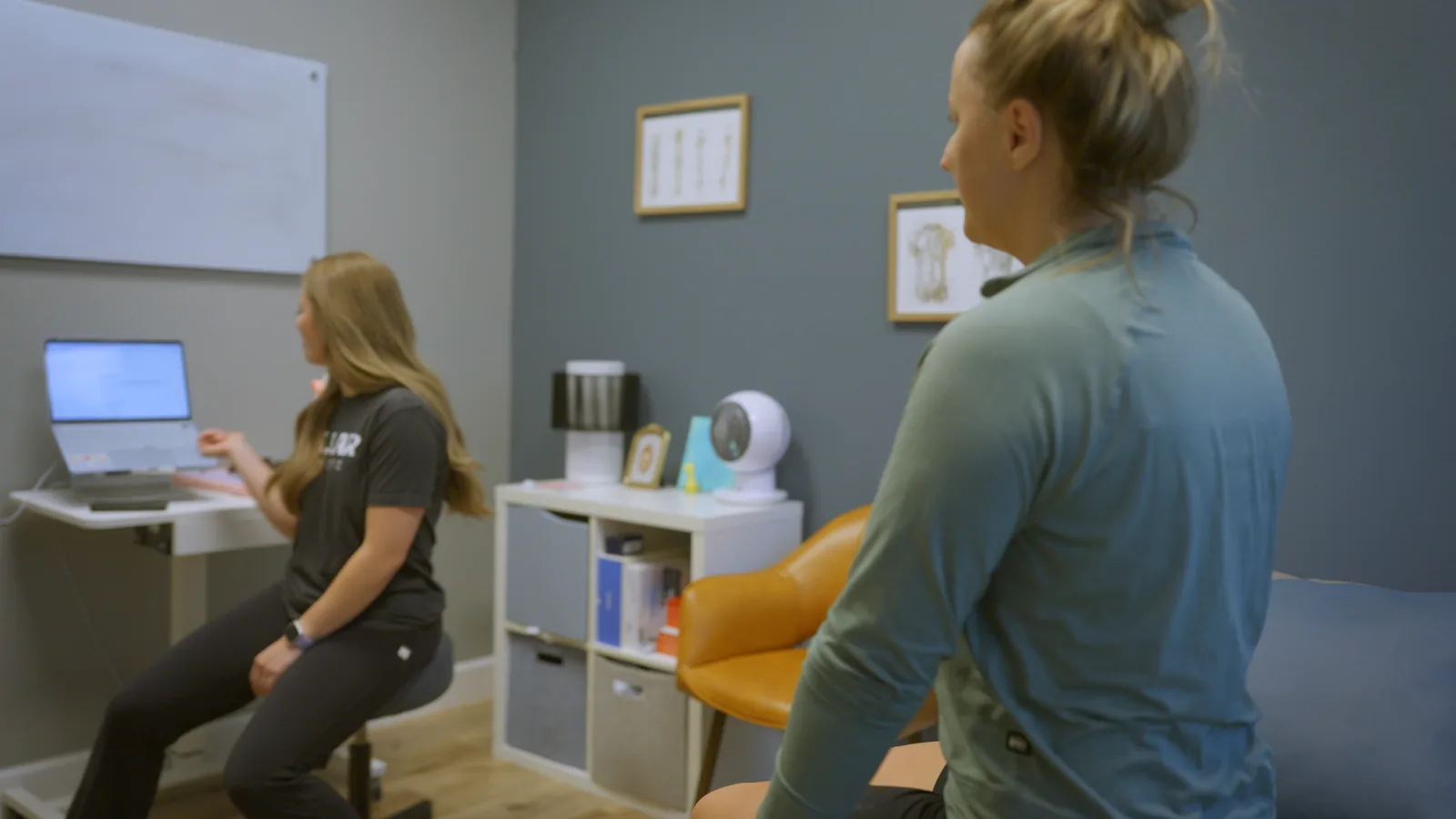 A physical therapist talking with a patient in a private treatment room