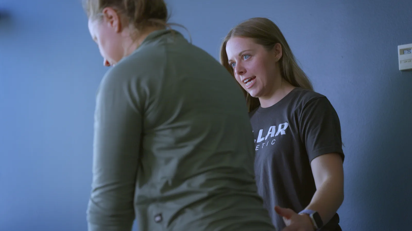 A physical therapist talking a patient through her next movement in the clinic gym
