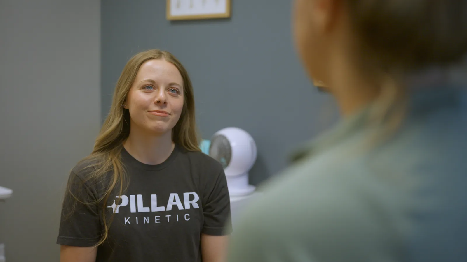 A pelvic health physical therapist smiling as she listens to a patient