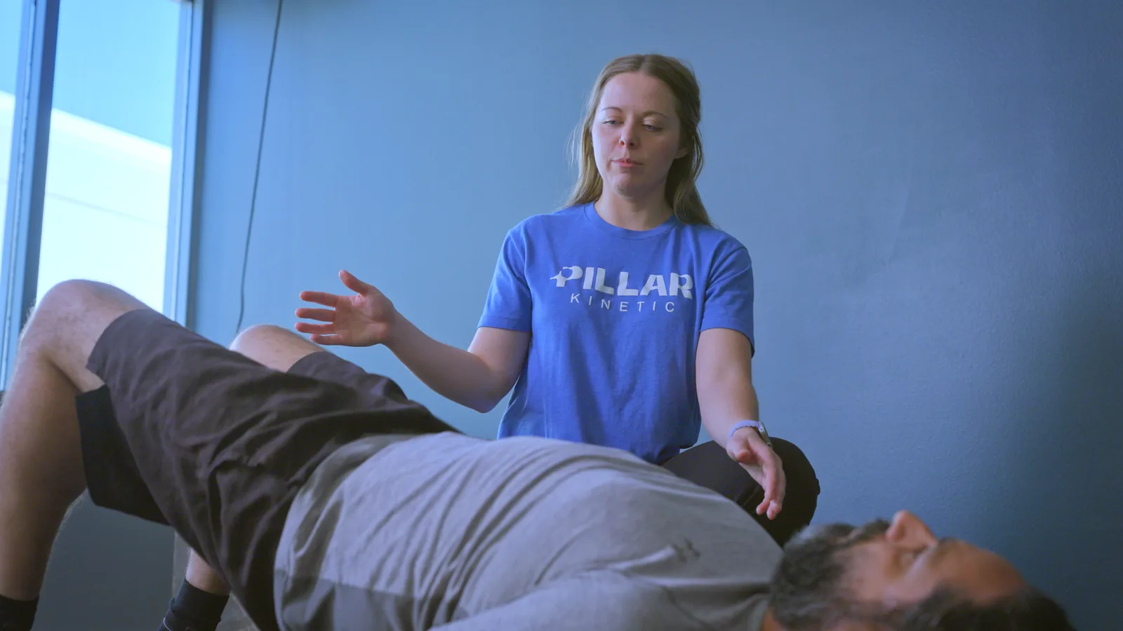 A physical therapist explaining the next exercise to a man lying on an exercise mat