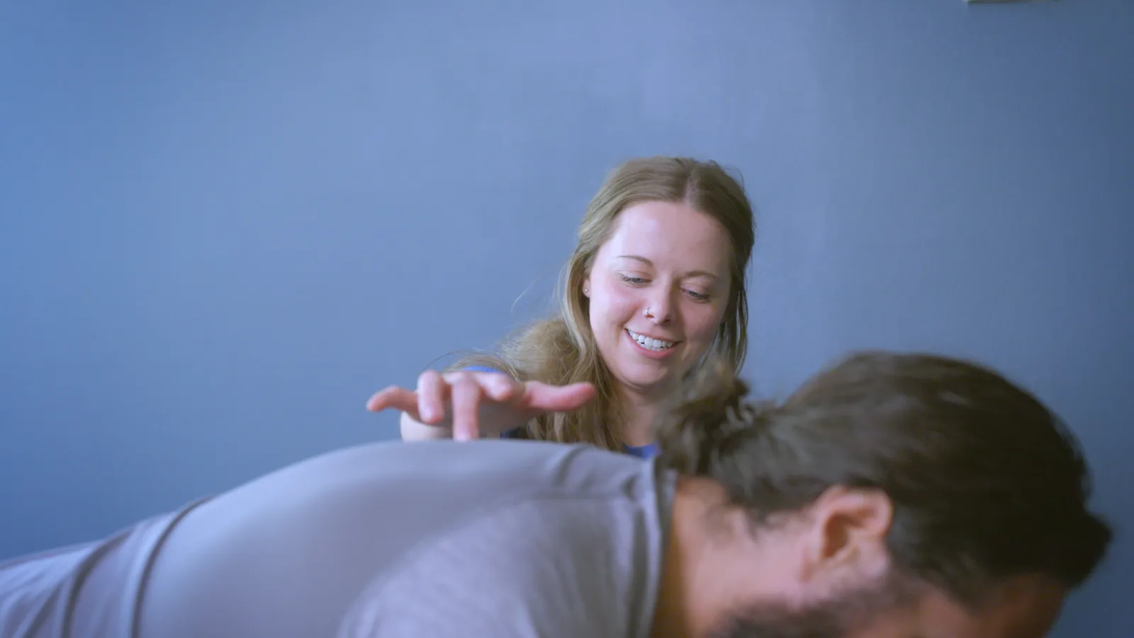 A physical therapist guiding a man through an exercise on his hands and knees