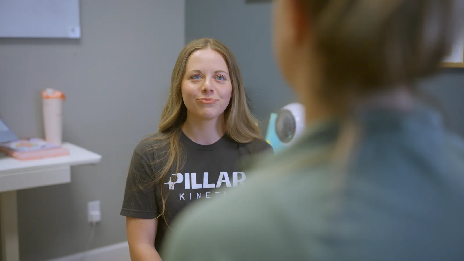 A physical therapist smiling as she talks with a patient in a consultation room
