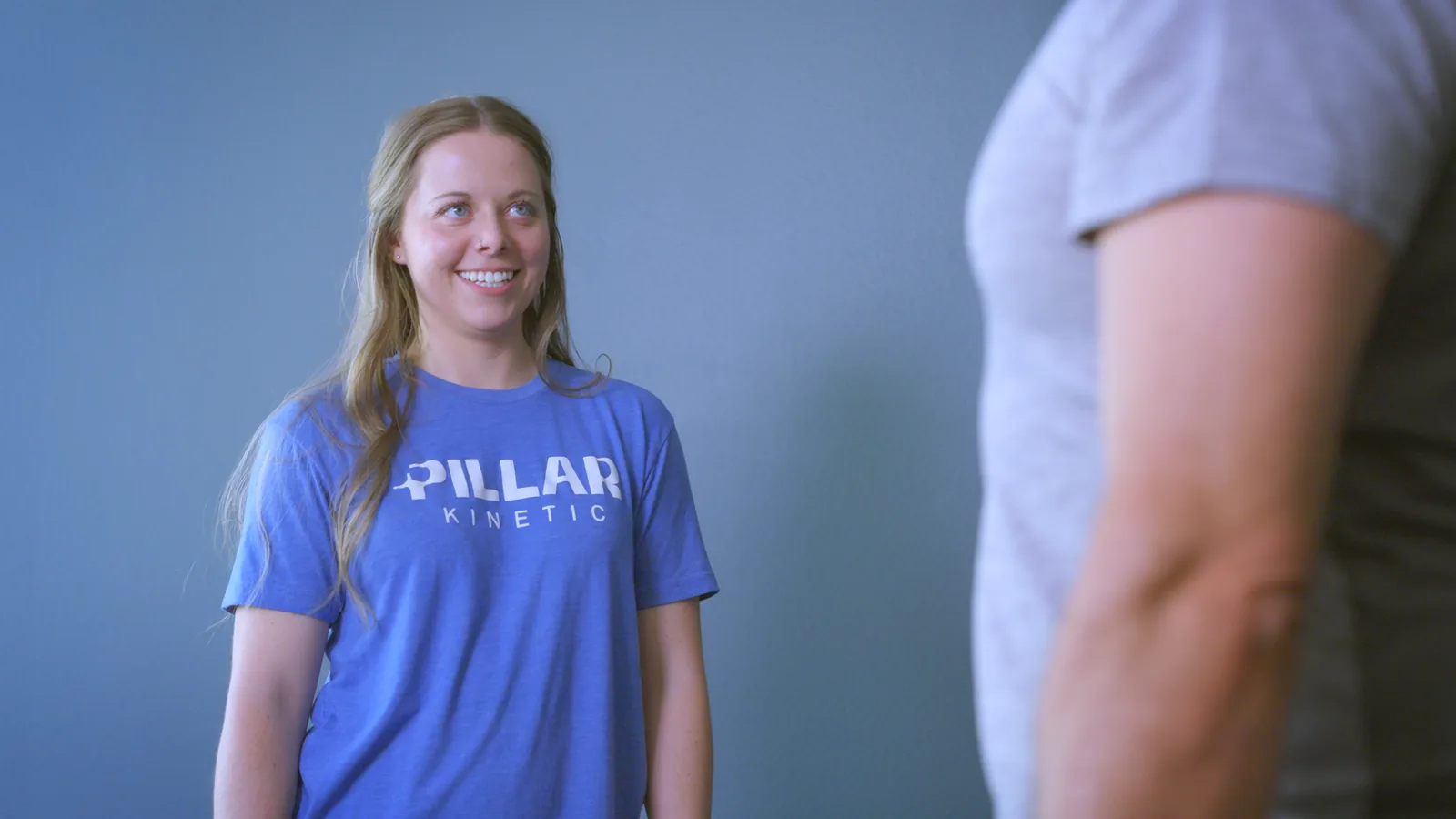 A smiling physical therapist listening to a patient during an evaluation