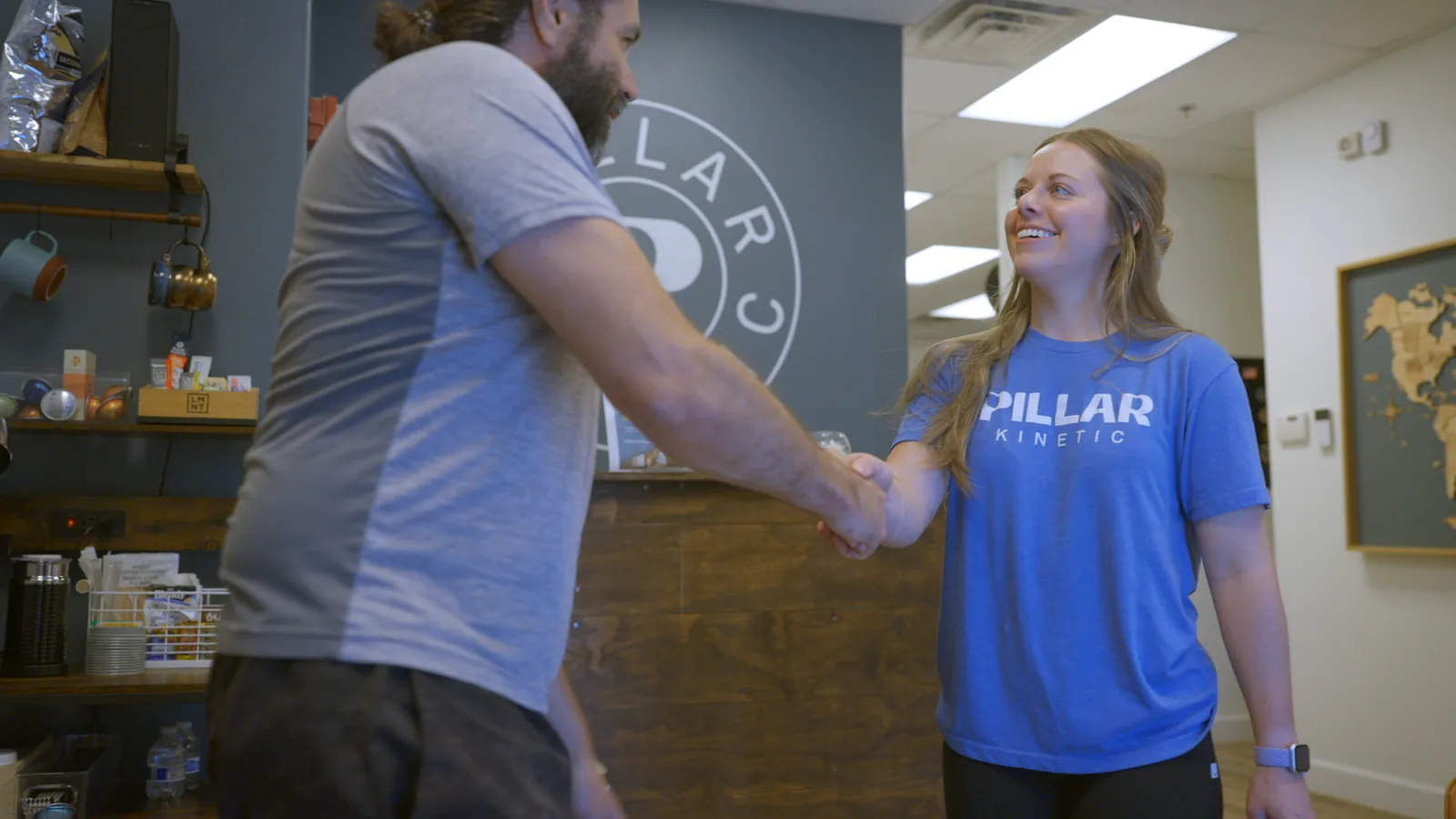 A physical therapist shaking hands with a patient at the clinic's front desk