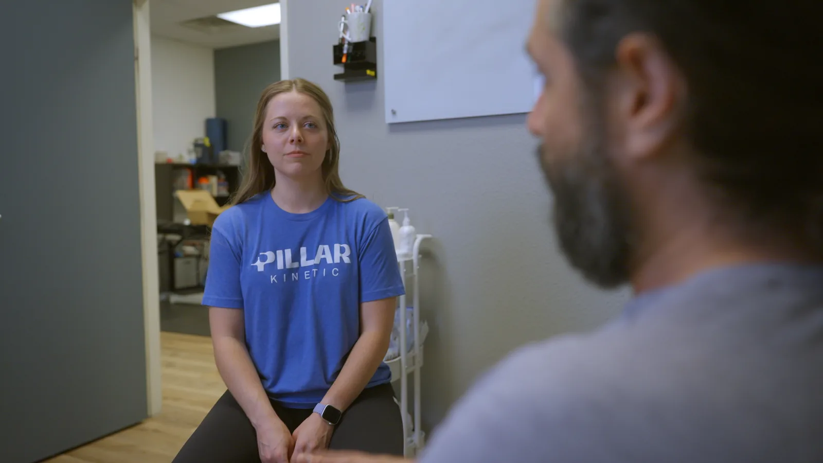 A physical therapist listening to a patient during an evaluation in a consultation room