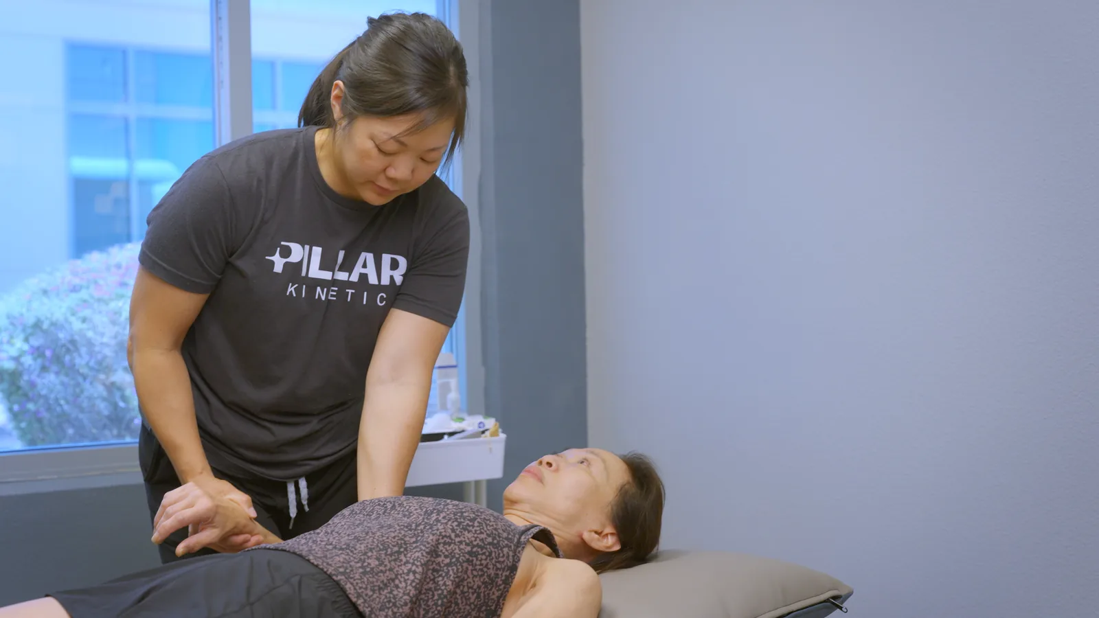 A physical therapist pressing on a patient's hip as she lies on the treatment table