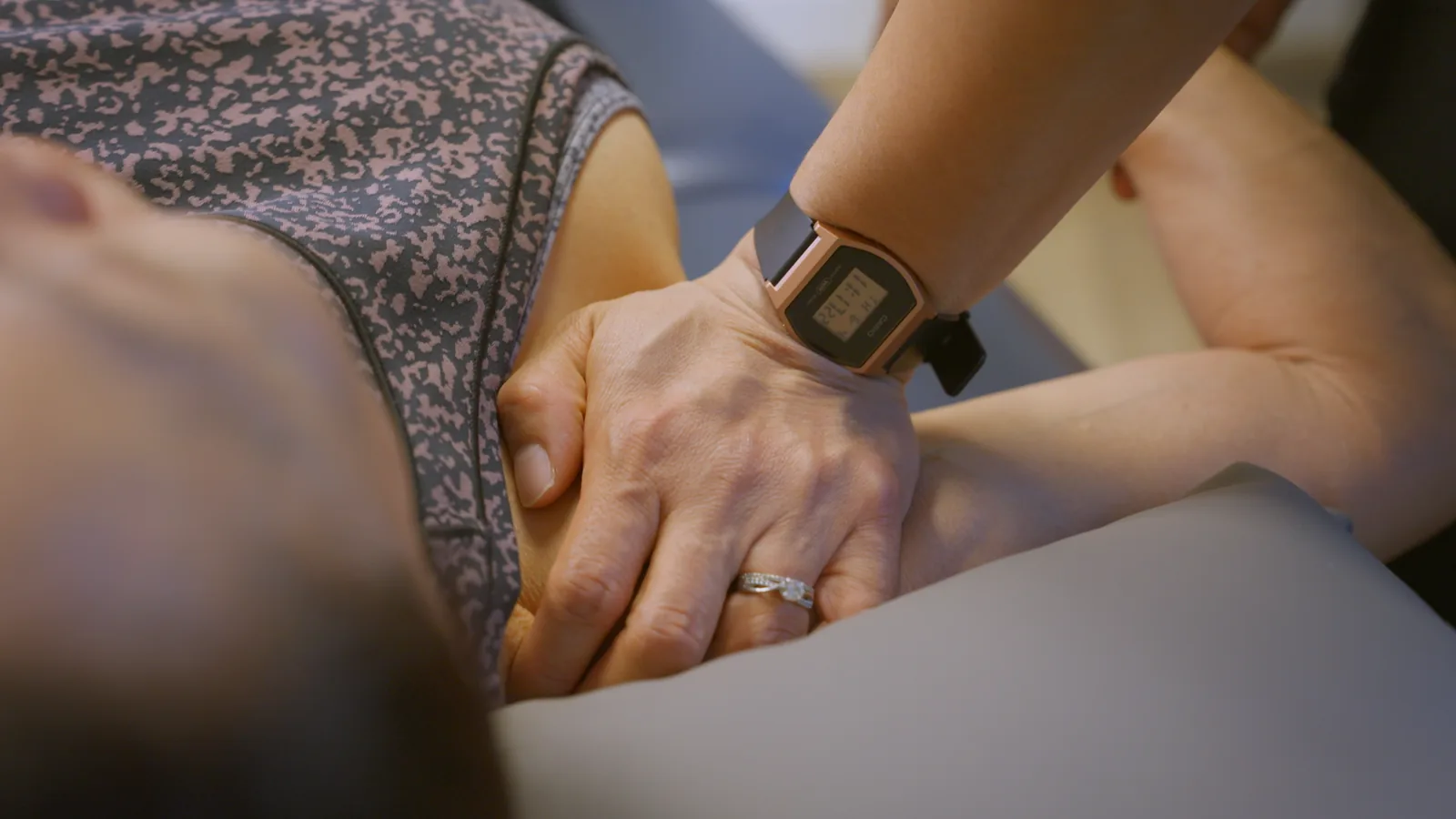 A physical therapist's hands working on the muscles at the front of a patient's shoulder